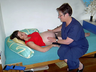 Hebamme die die typischen Handgriffe macht um die Lage des Babys festzustellen